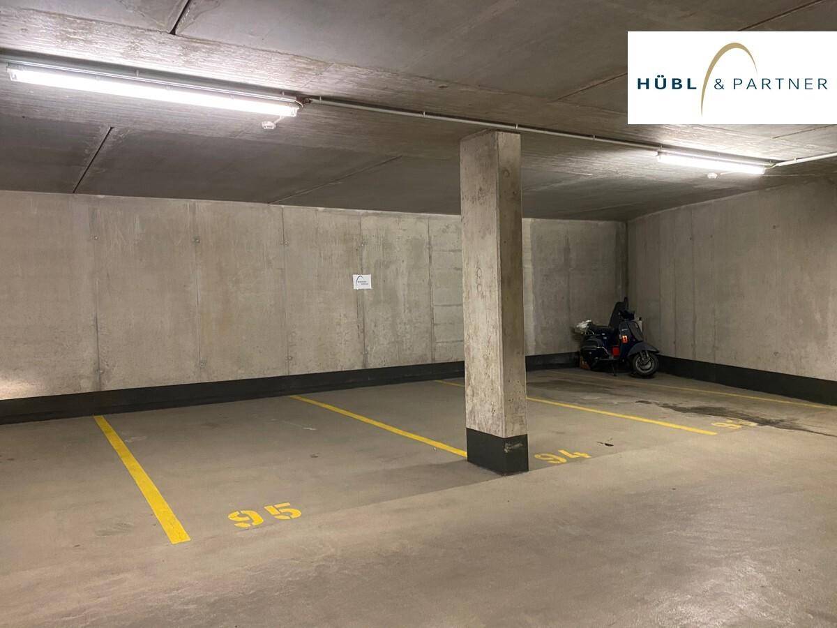 Tiefgaragenstellplätze mit Betonwänden und Decken, beleuchtet mit Leuchtstoffröhren und einem Roller.