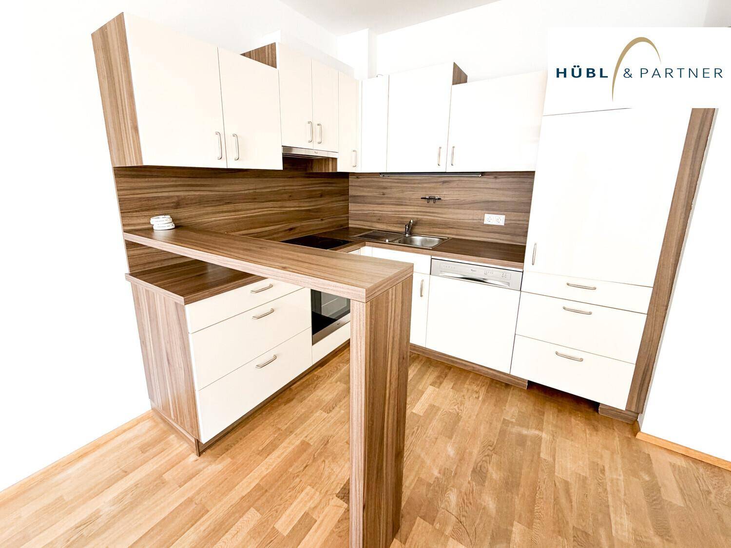 Moderne Einbauküche mit weißen Schränken, Holzdetails und einer praktischen Frühstücksbar.