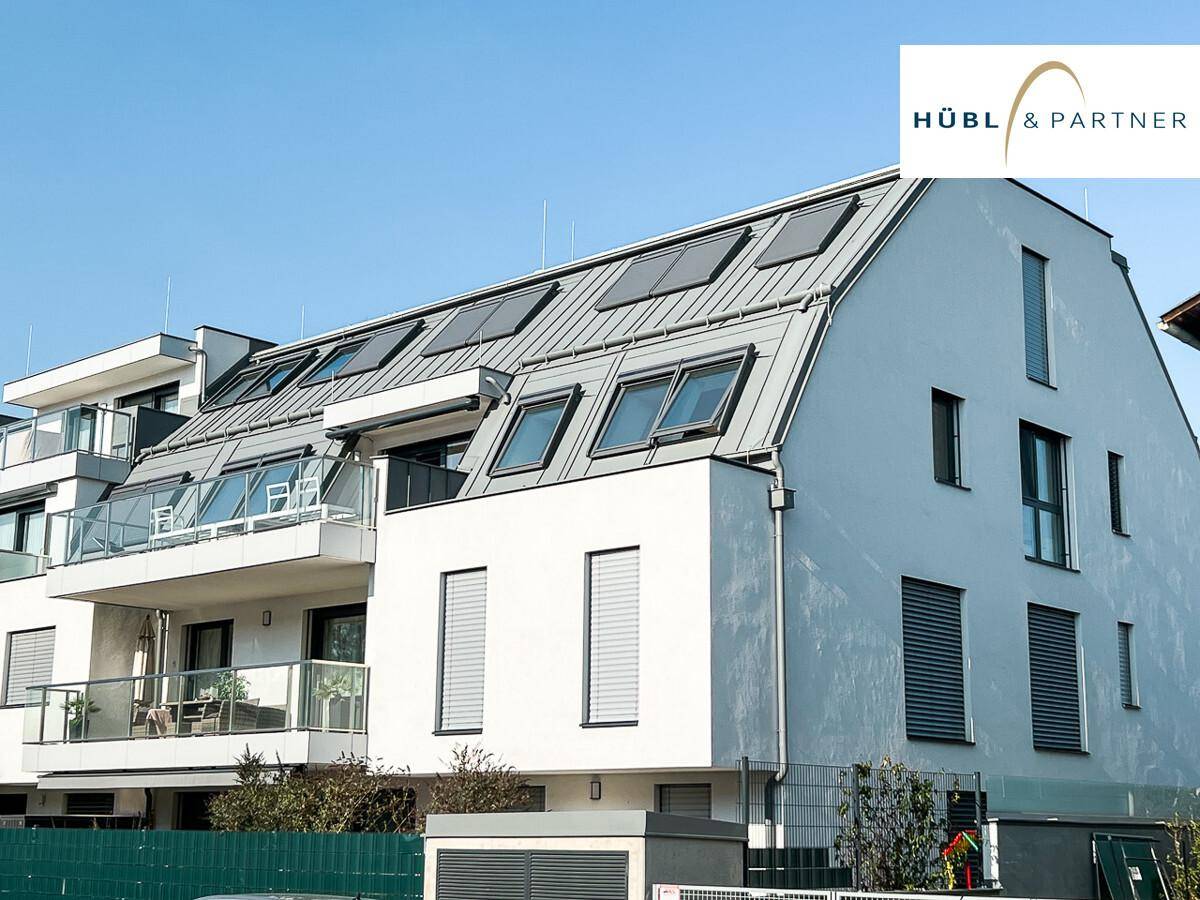 Detailansicht der modernen Wohnanlage mit Balkonen, Dachfenstern und weißer Fassade.
