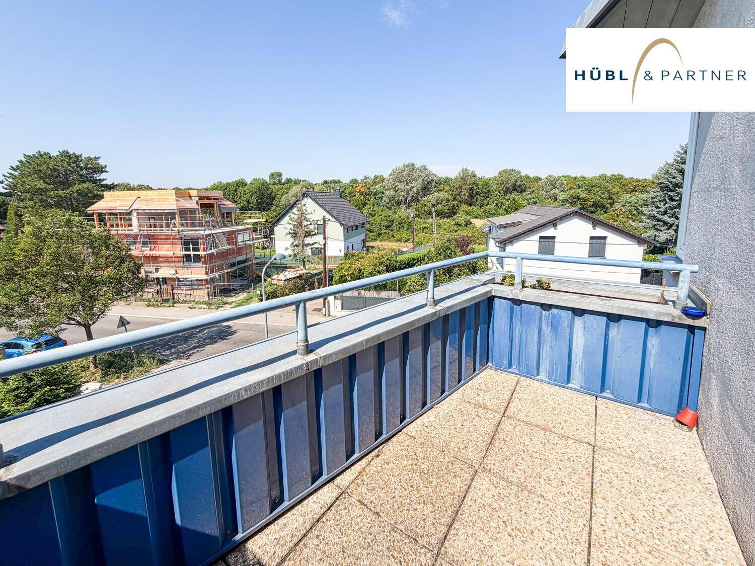Geräumiger Balkon mit blauer Brüstung und Blick auf die umliegende Wohngegend.