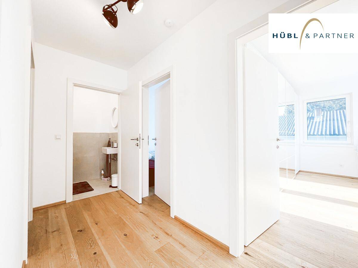 Heller Flur mit Holzboden, der zu einem Badezimmer und einem Schlafzimmer führt.