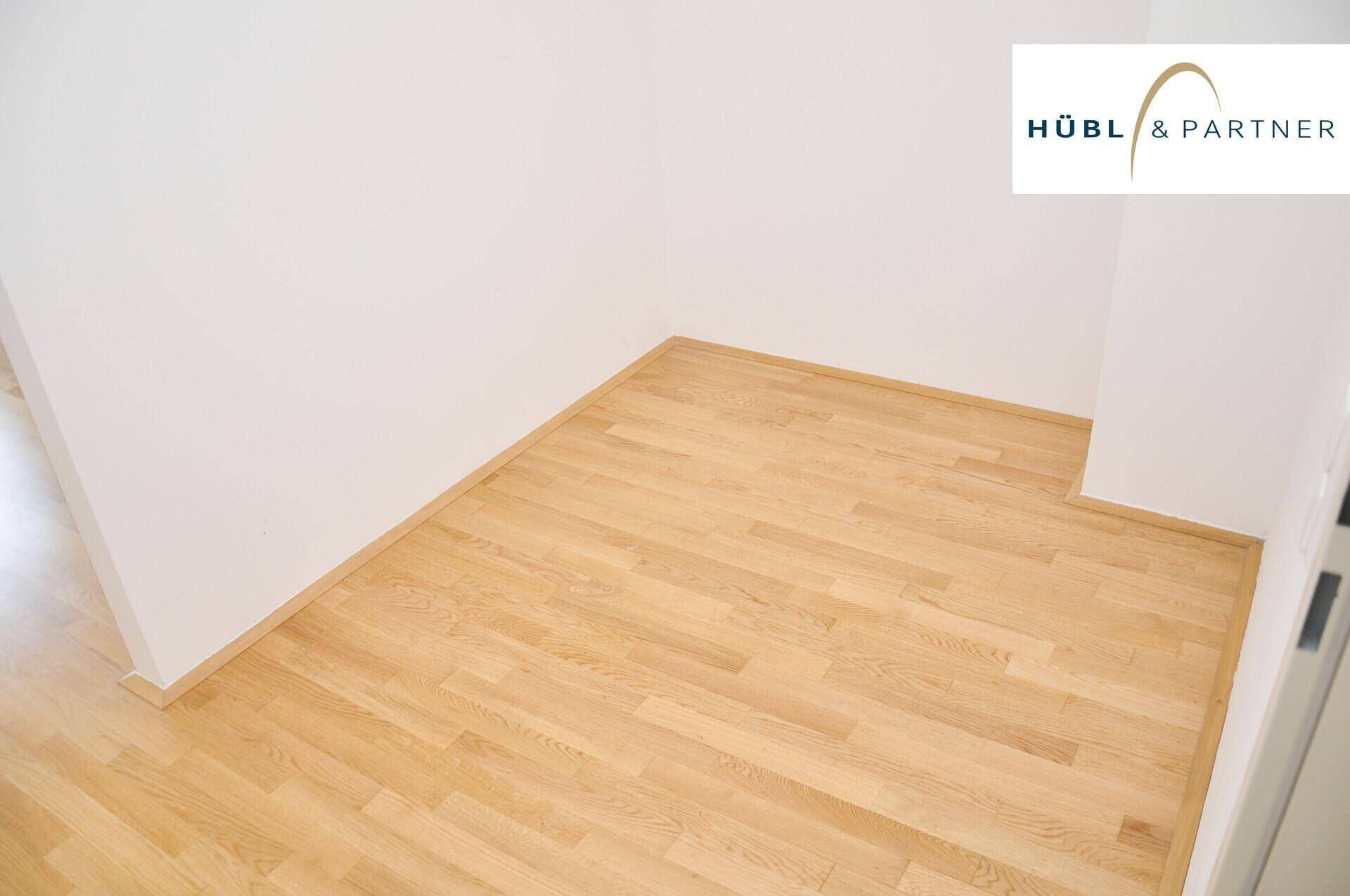 Detailaufnahme von hochwertigem Parkettboden in einem hellen Raum, unterstreicht die Qualität der Materialien.