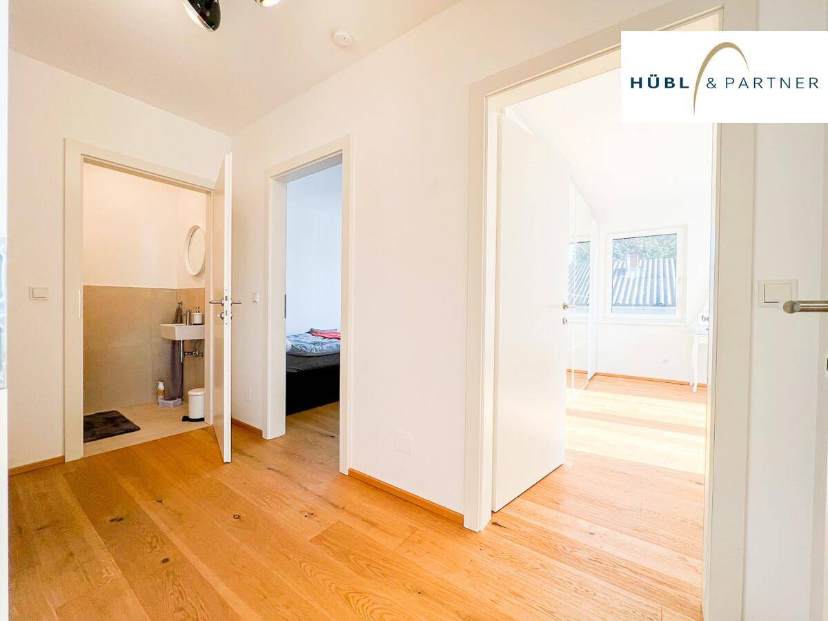 Heller Flur mit Holzboden, der zu einem Badezimmer und einem Schlafzimmer führt.