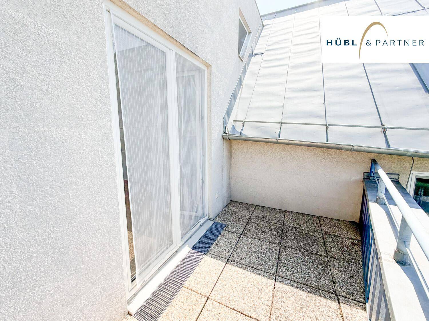 Heller Balkon mit Fliesenboden und Schiebetür, ideal für entspannte Stunden im Freien.