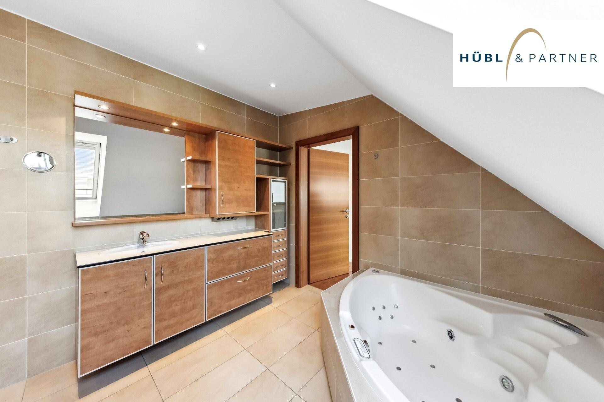 Geräumiges Badezimmer mit Whirlpool-Badewanne, Holzmöbeln und Fliesenboden.