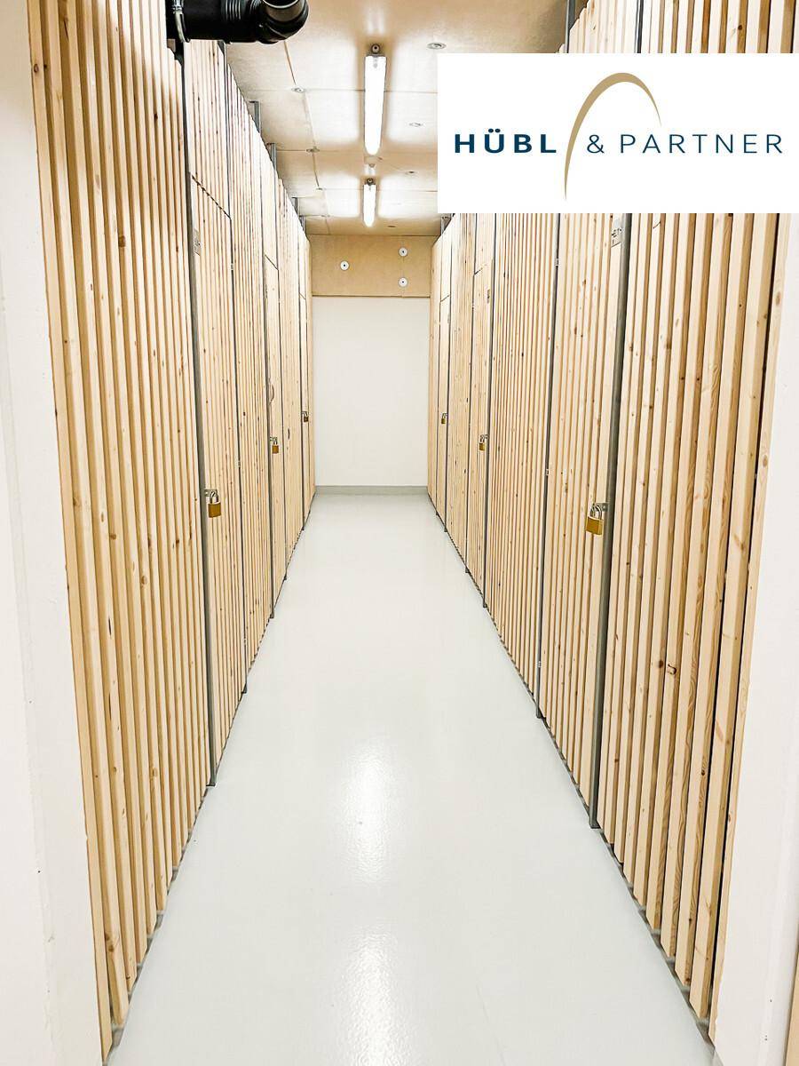 Langer Flur mit zahlreichen individuellen Abstellräumen, gekennzeichnet durch Holzlattenwände.