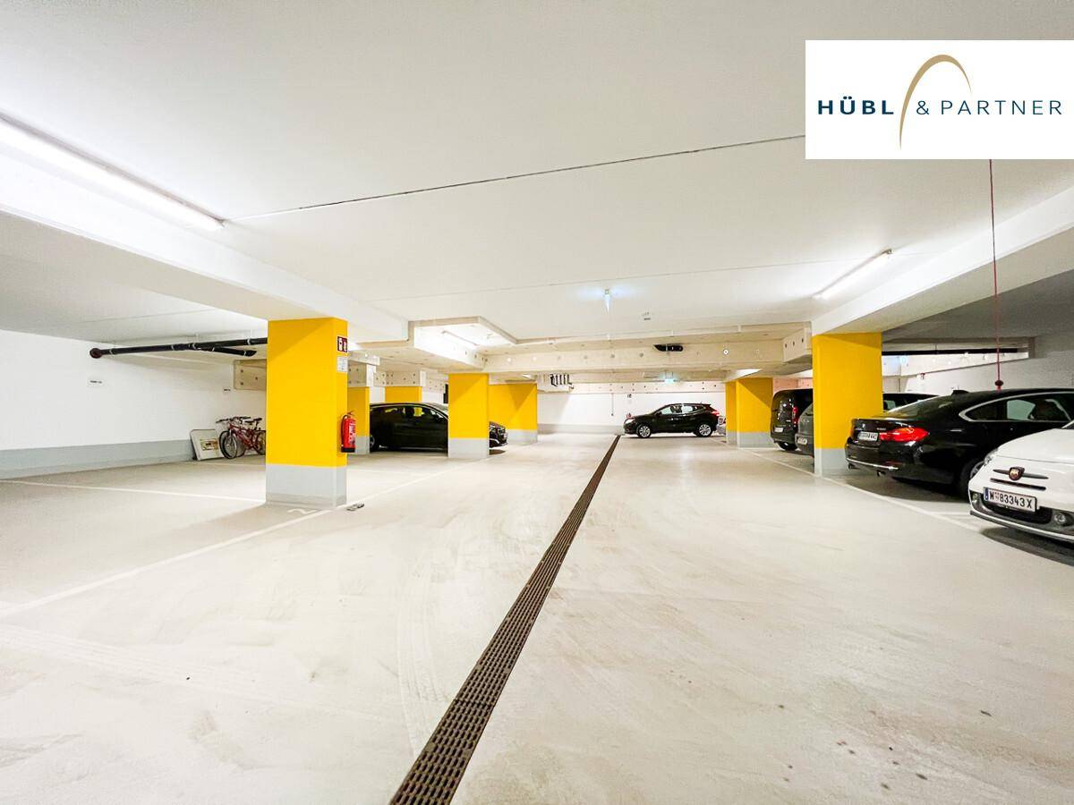 Geräumige Tiefgarage mit mehreren geparkten Autos und gelben Säulen.