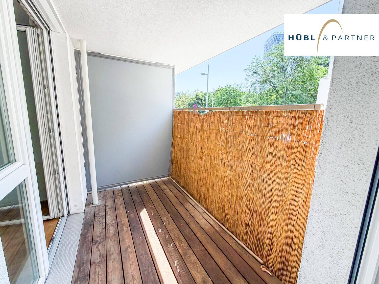 Gemütlicher Balkon mit Holzboden und Sichtschutz, ideal zum Entspannen im Freien.