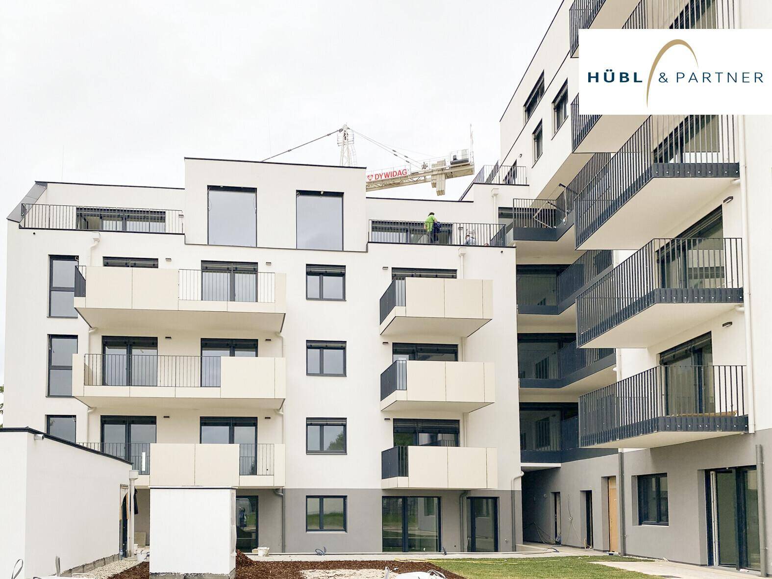 Moderne Wohnanlage mit weißer Fassade, großen Fenstern und zahlreichen Balkonen.