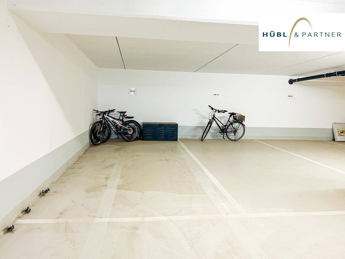 Tiefgaragenstellplatz mit Fahrrädern und weiß gestrichenen Wänden.