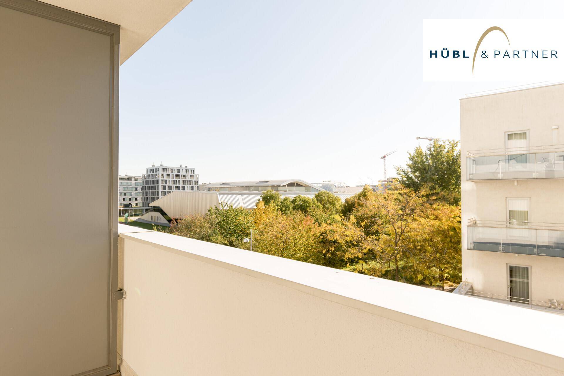 Weitblick vom Balkon über die Stadt mit umliegenden Gebäuden und grünen Bäumen.