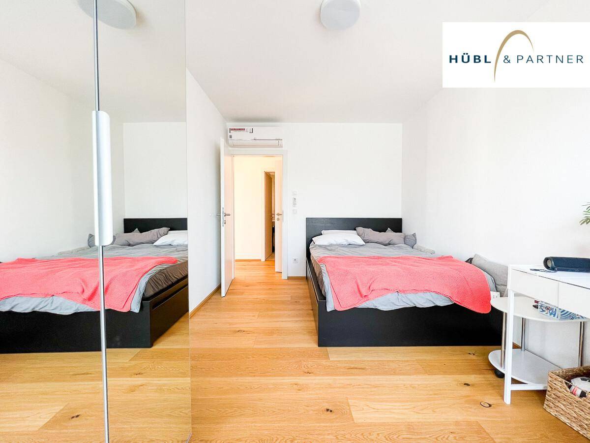 Geräumiges Schlafzimmer mit Holzboden, zwei Einzelbetten und einem Spiegelschrank.