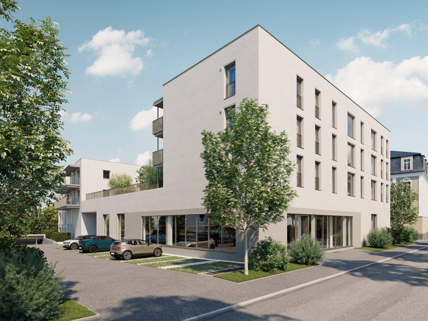 Modernes Wohngebäude mit Parkplätzen und großen Fensterfronten im Erdgeschossbereich.