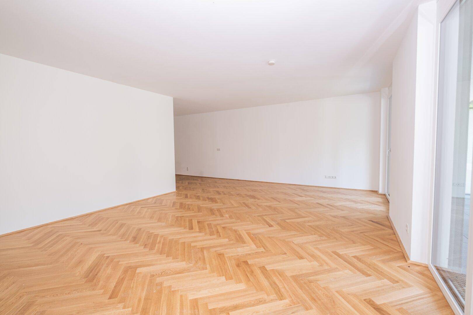 Geräumiges, helles Zimmer mit elegantem Fischgrätparkett und viel Tageslicht.