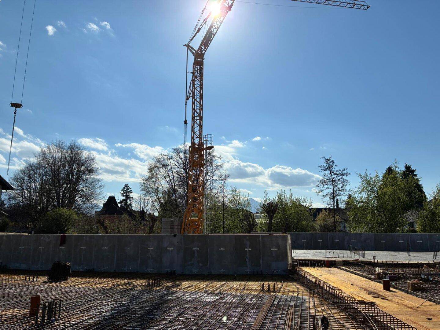 Baustelle mit großer Bewehrung auf der Fundamentplatte und einem hohen Baukran.