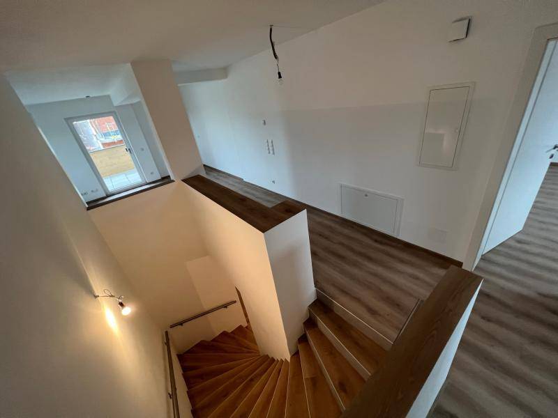 Heller Treppenaufgang mit Holzstufen und Laminatboden, der verschiedene Ebenen des Hauses verbindet.