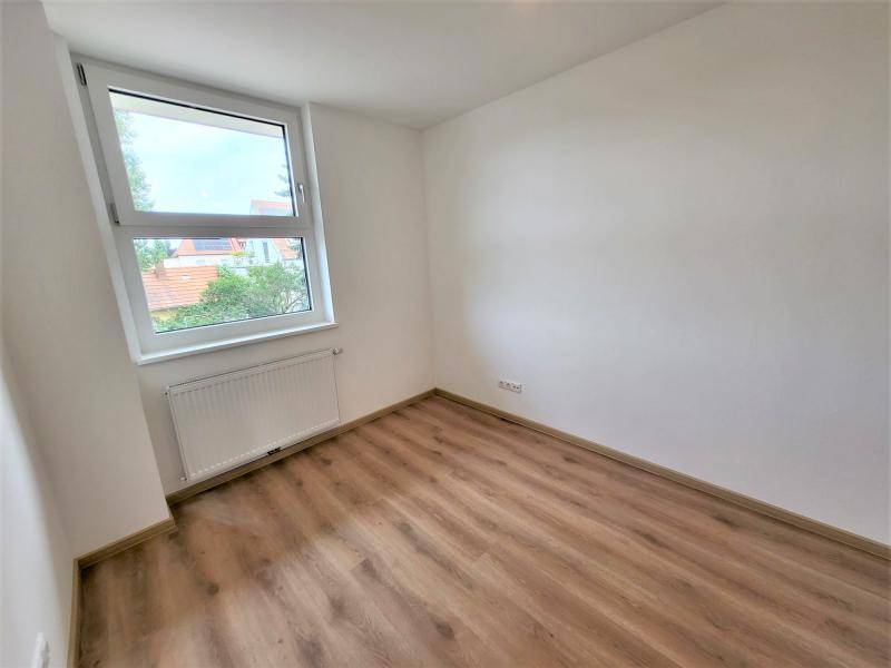 Ruhiges Zimmer mit Blick ins Grüne und hellem Laminatboden.