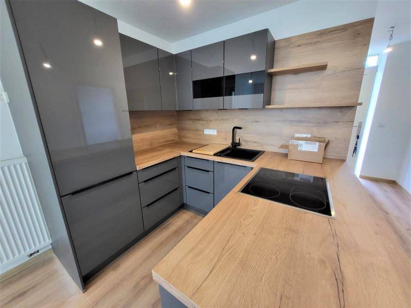 Detailansicht der modernen Küche mit glänzenden grauen Schränken und Holz-Arbeitsflächen.