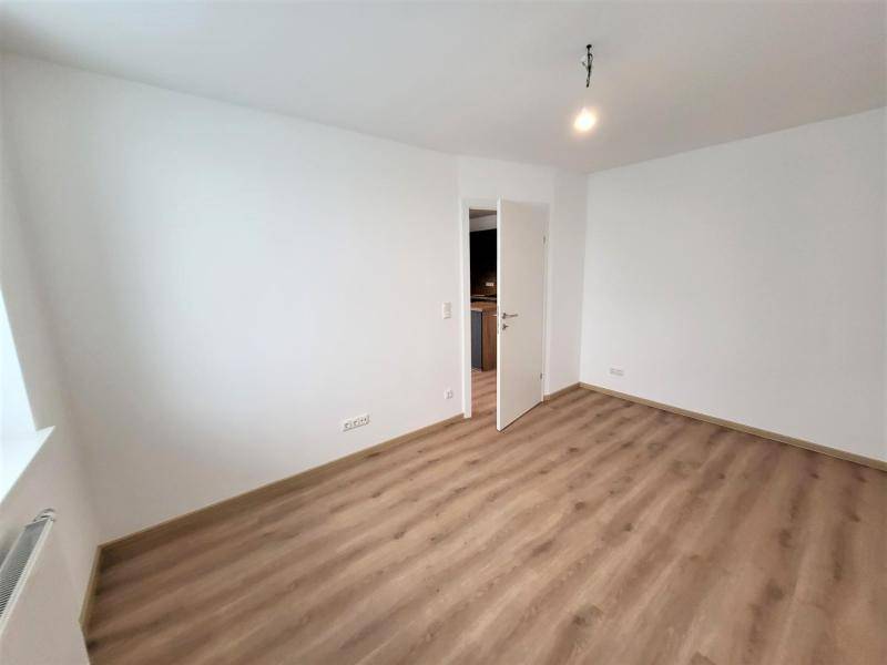 Geräumiges, helles Zimmer mit Laminatboden und weiß gestrichenen Wänden.