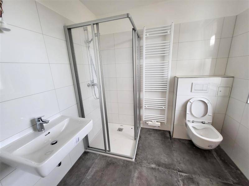 Modernes Badezimmer mit Duschkabine, Waschbecken und beheiztem Handtuchhalter.