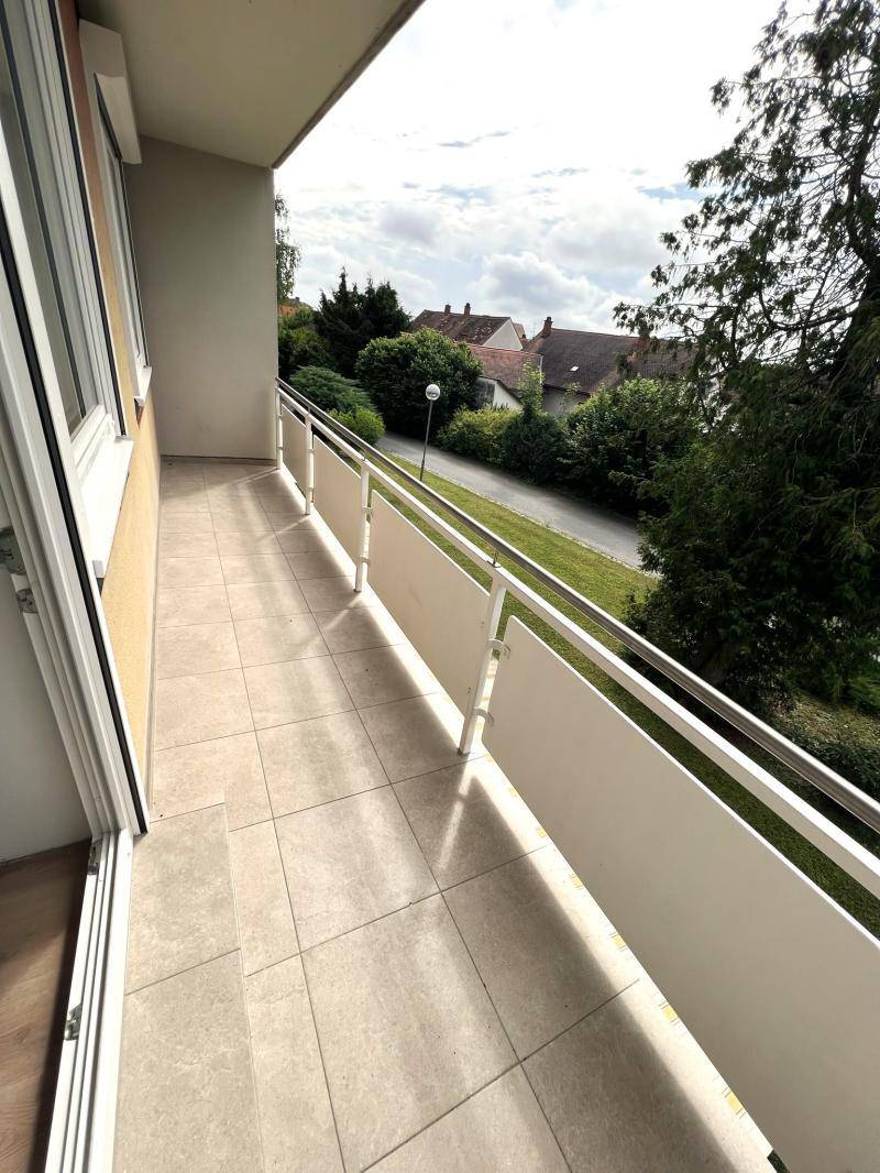 Heller Balkon mit Fliesenboden und Blick auf die grüne Umgebung.