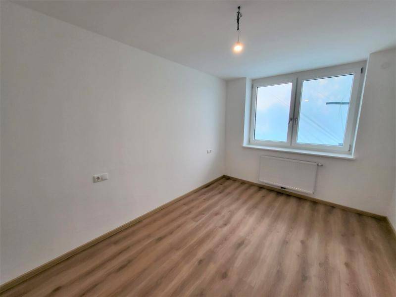 Lichtdurchflutetes Zimmer mit großem Fenster und Heizkörper unter der Fensterbank.