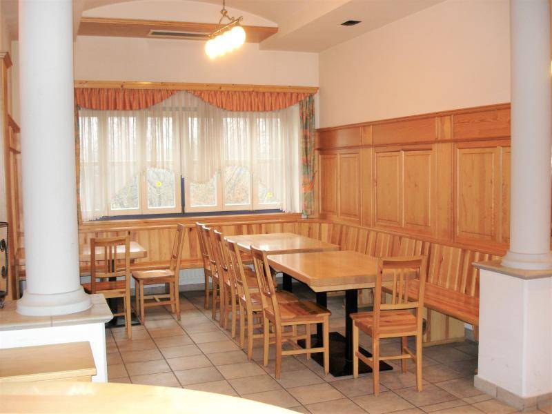 Gemütlicher Essbereich mit Holztischen, Stühlen und durchgehenden Sitzbänken an der Wand.