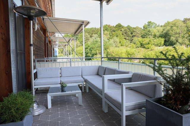 Geräumiger Balkon mit bequemen Loungemöbeln und Blick ins Grüne, ideal zum Entspannen im Freien.