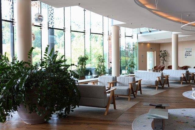 Heller, moderner Loungebereich mit großen Fensterfronten und viel Grünblick.