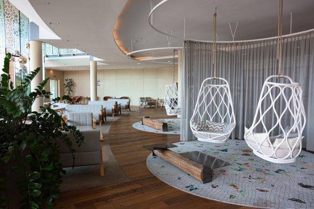 Großzügiger Loungebereich mit modernen Hängesesseln und Holzboden.