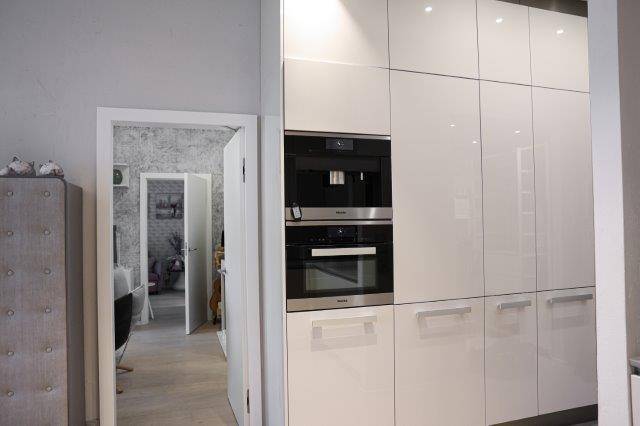 Hochglanz-Küchenschränke mit integriertem Backofen und Kaffeemaschine in modernem Design, hochwertige Geräte.