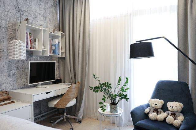 Heller Arbeitsbereich mit Schreibtisch, Monitor und bequemen Stühlen am Fenster, ideal für Homeoffice.
