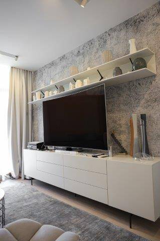 Moderner Wohnbereich mit großem Fernseher, weißem Sideboard und strukturierter Wandtapete, stilvoll eingerichtet.