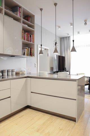 Moderne Küche mit glänzenden Schränken, integrierten Regalen und heller Arbeitsplatte, funktional und stilvoll.