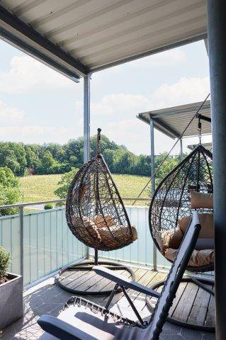 Gemütlicher Balkon mit Hängesesseln und weitem Blick ins Grüne.