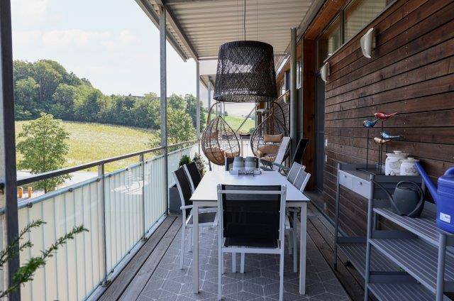 Heller Balkon mit Esstisch, Hängesesseln und weitem Blick über die Landschaft, bietet viel Erholung.