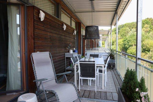 Großer Balkon mit Esstisch, Stühlen und Blick auf die umliegende Natur, perfekt für Mahlzeiten im Freien.