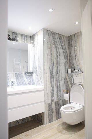 Modernes WC mit Waschtisch, wandhängendem WC und Marmoroptik-Fliesen, sehr sauber und stilvoll.
