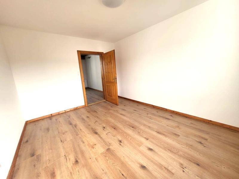 Leeres Zimmer mit Laminatboden und weiß gestrichenen Wänden, ideal für ein Schlafzimmer.