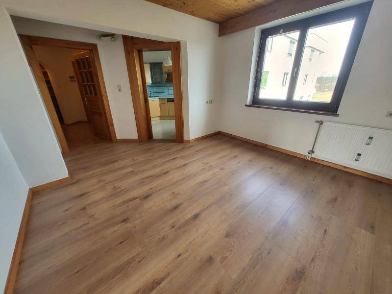 Geräumiges Zimmer mit Laminatboden und Holzdecke, bietet Zugang zur Küche.