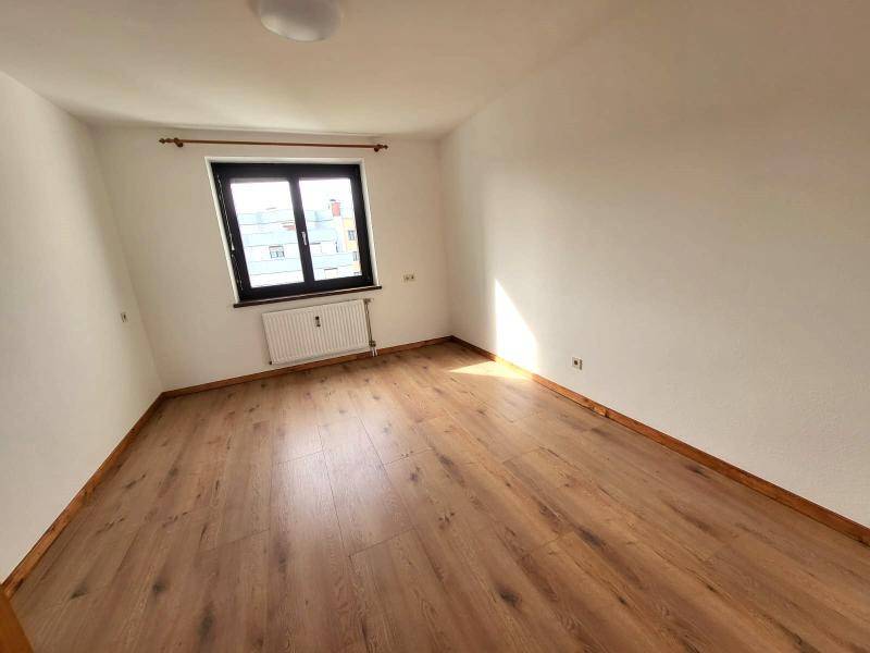 Helles Schlafzimmer mit Laminatboden und Fenster, bereit zur Einrichtung.