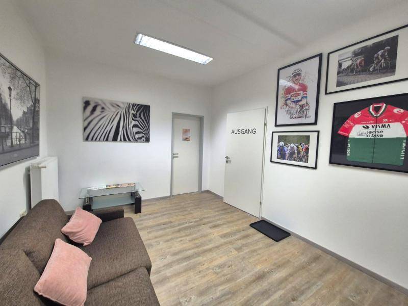Gemütlicher Wartebereich mit Sofa, Bildern an der Wand und einem Ausgangsschild.
