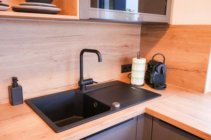 Detailaufnahme der modernen Küchenspüle mit schwarzem Wasserhahn und Holz-Arbeitsplatte.