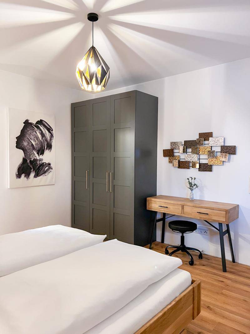 Schlafzimmer mit großem Kleiderschrank, Schreibtisch und moderner Dekoration, funktional und stilvoll.
