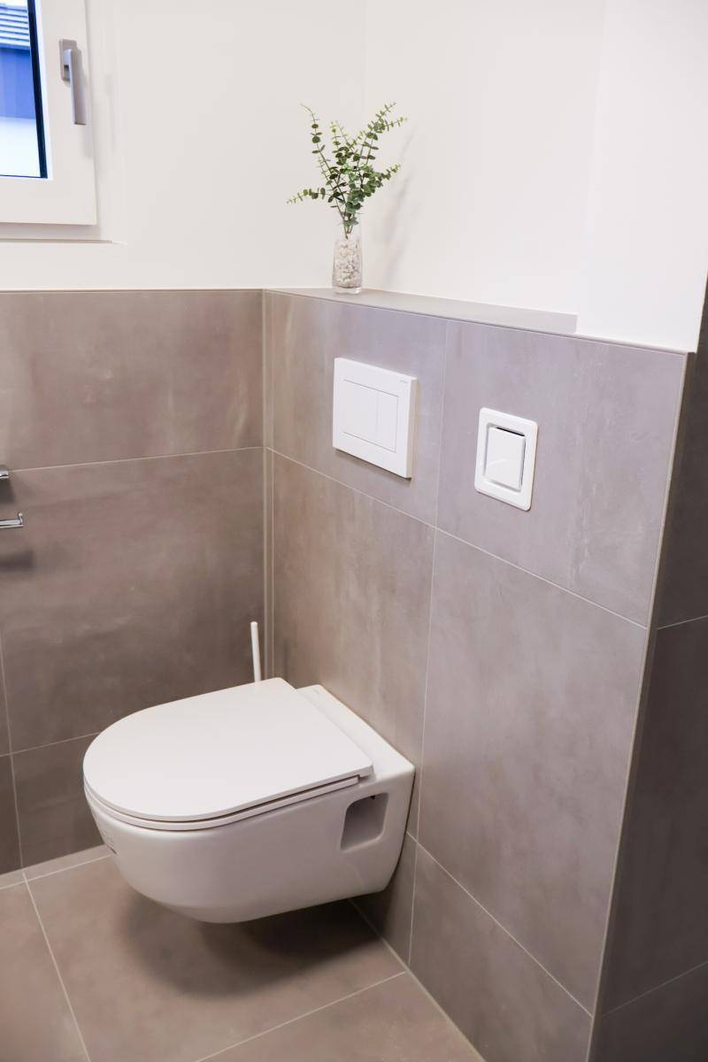 Modernes WC mit wandhängender Toilette und neutralen Fliesen, bietet ein sauberes Design.