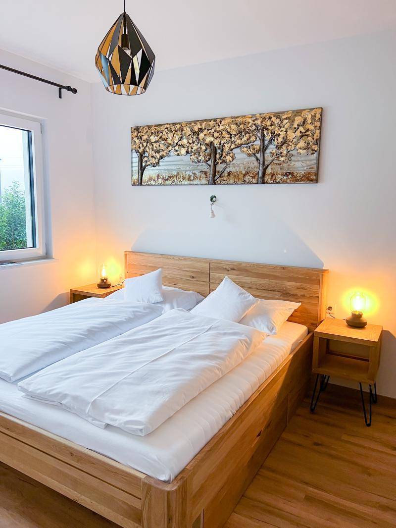 Schlafzimmer mit hellem Holzbett, Nachttischen und Fenster, bietet eine ruhige Schlafumgebung.