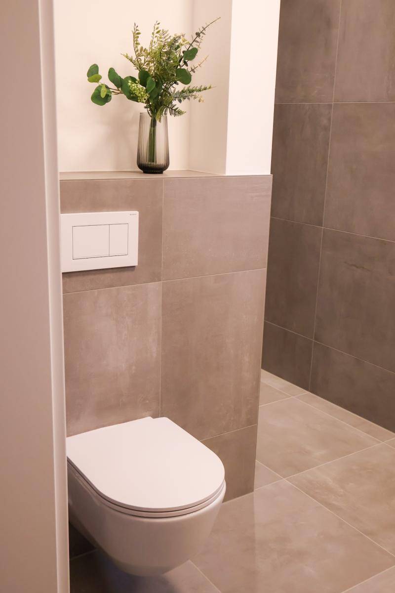 Wandhängende Toilette in einem modern gefliesten Badezimmer, mit minimalistischem Design.