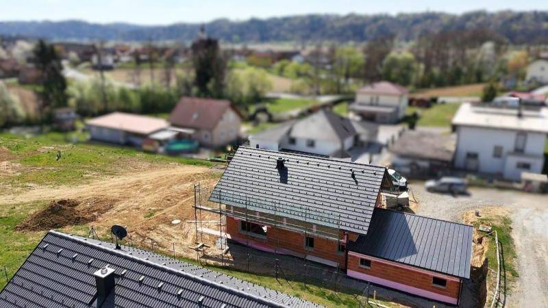 Blick von oben auf ein im Bau befindliches Haus in einer ländlichen Siedlung.