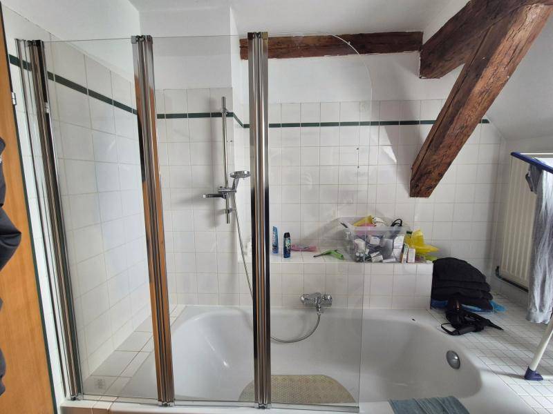 Badezimmer mit Badewanne, Duschabtrennung und weißen Fliesen im Dachgeschoss, funktional und hell.