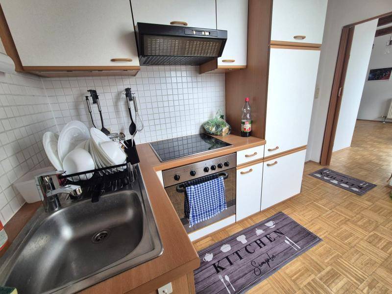 Funktionale Küche mit weißen Schränken, Kochfeld und Spüle, ausgestattet für den täglichen Gebrauch und Kochen.